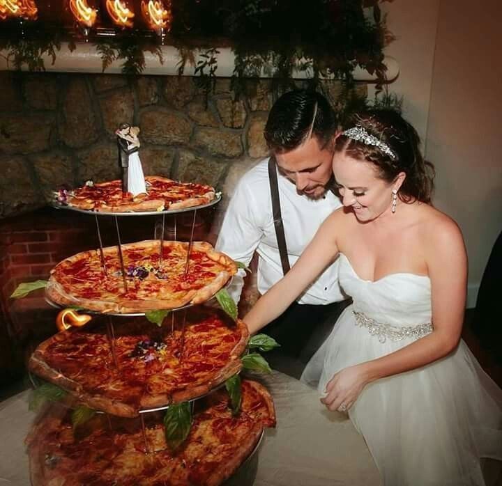 the bride and groom are cutting their pizzas