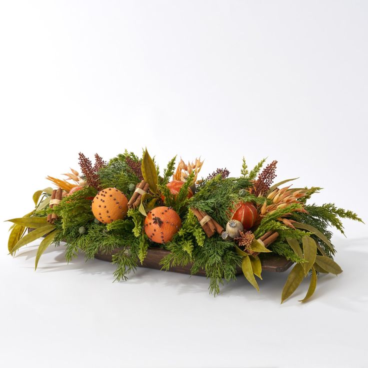 an arrangement of foliage and pumpkins on a white background