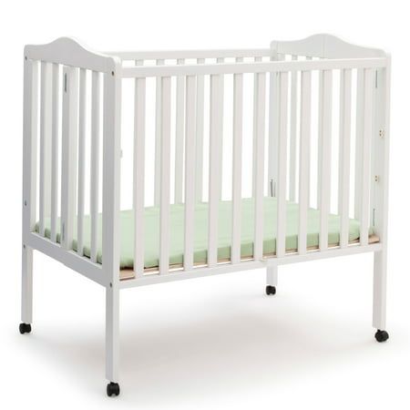 a white crib with green sheets on the bottom and side rails, in front of a white background