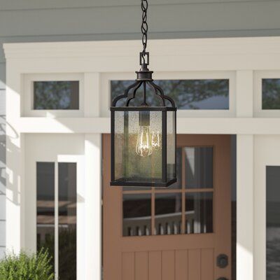 an outdoor light hanging from the side of a house in front of a brown door