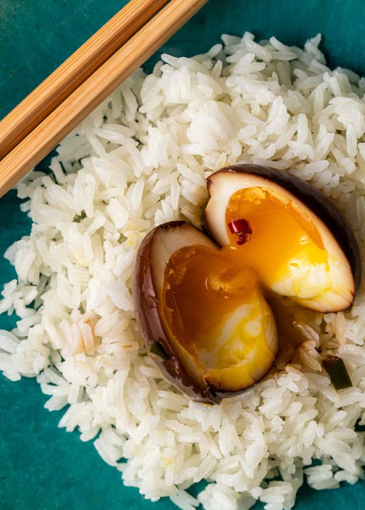 chopsticks on top of rice with an egg in the middle and two pieces of fruit