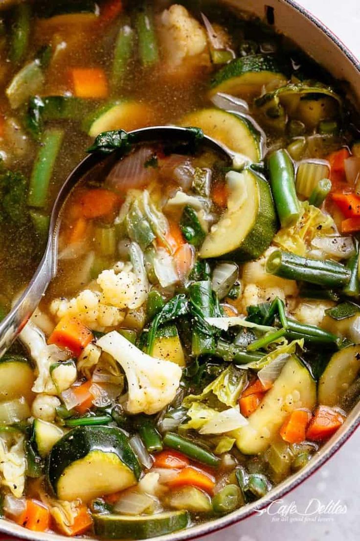 a pot full of vegetable soup with a spoon in it