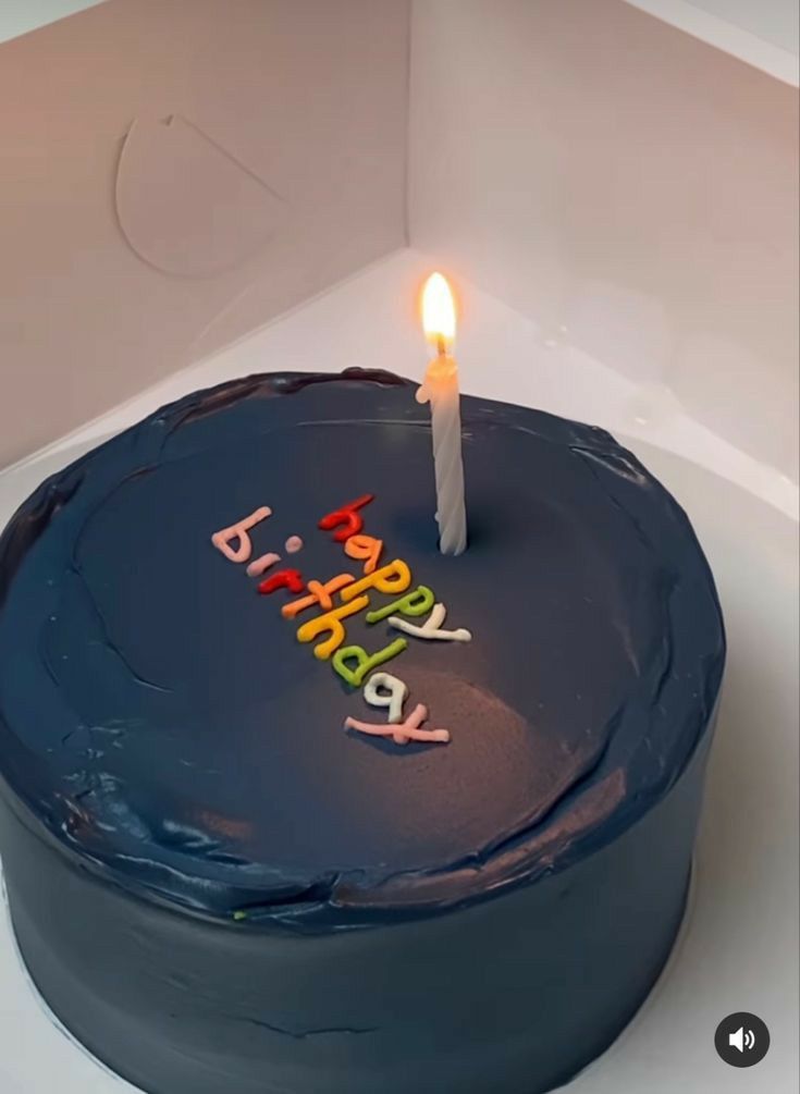 a blue birthday cake with a lit candle on it's top that says happy birthday