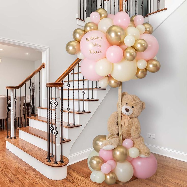 a teddy bear sitting on top of a bunch of balloons in front of a staircase