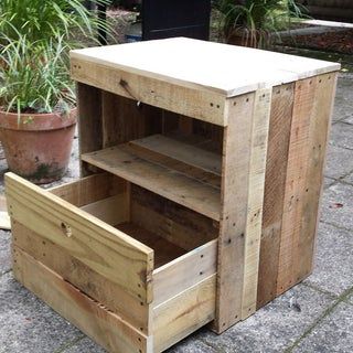 a wooden cabinet sitting on top of a sidewalk next to a potted planter