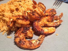 some shrimp and rice on a plate with a fork next to the food that is ready to be eaten