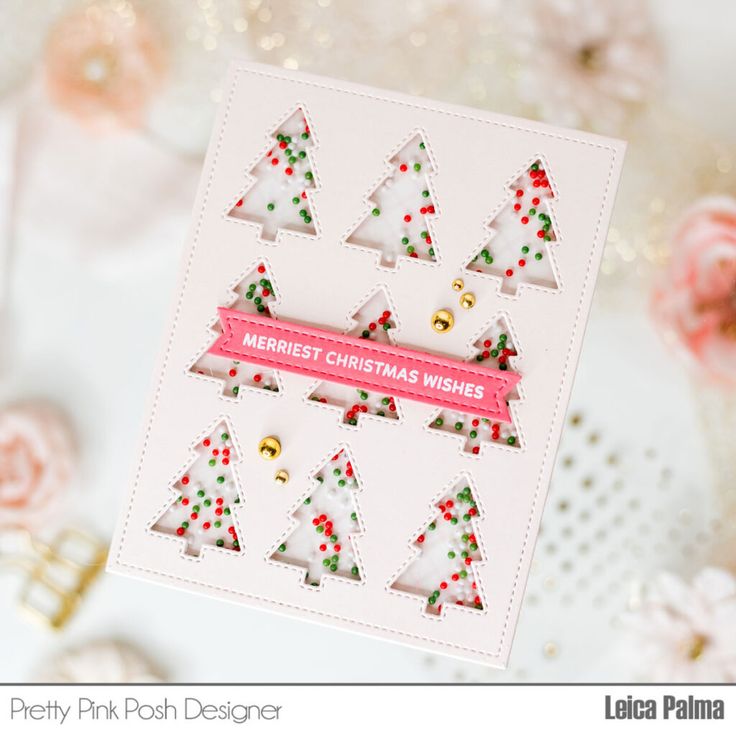 a close up of a card with christmas trees on it and pink ribbon in the middle