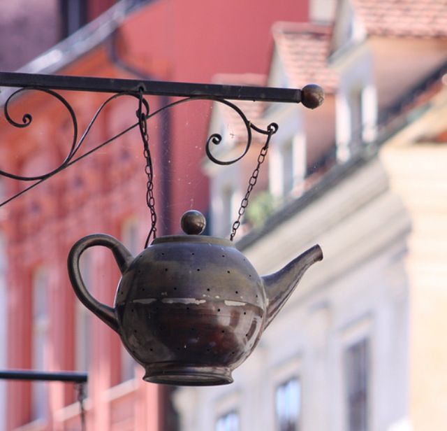 an old teapot hanging from the side of a building