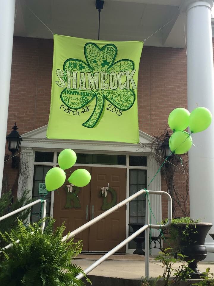 green balloons are floating in front of a building with a shamrock sign on the door