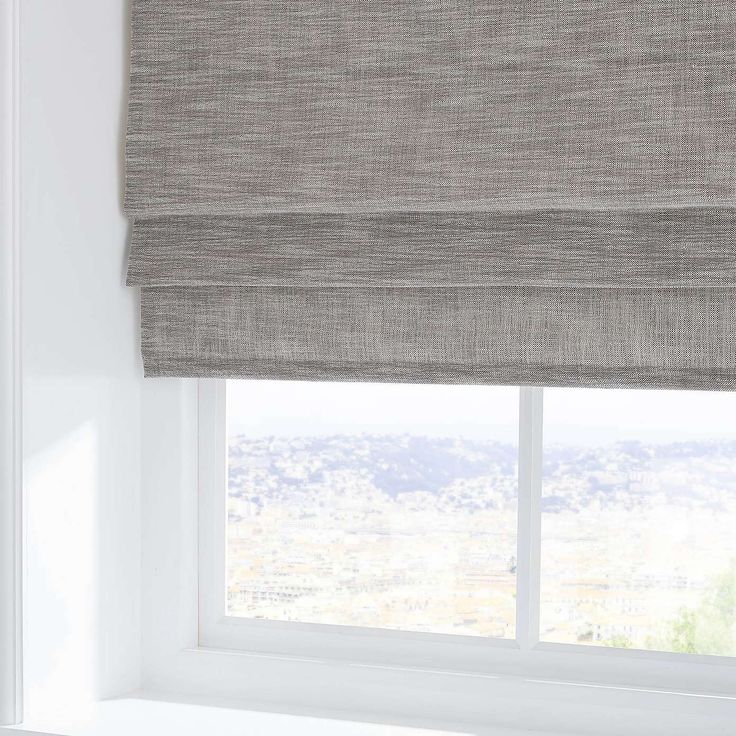 an open window with roman blind in grey linen, overlooking the city skyline and mountains