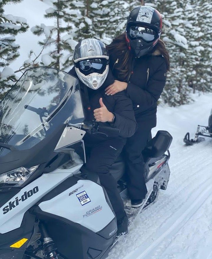 two people on a snowmobile giving the thumbs up