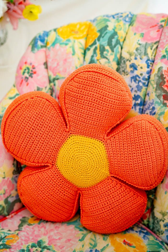 an orange knitted flower sitting on top of a colorful chair