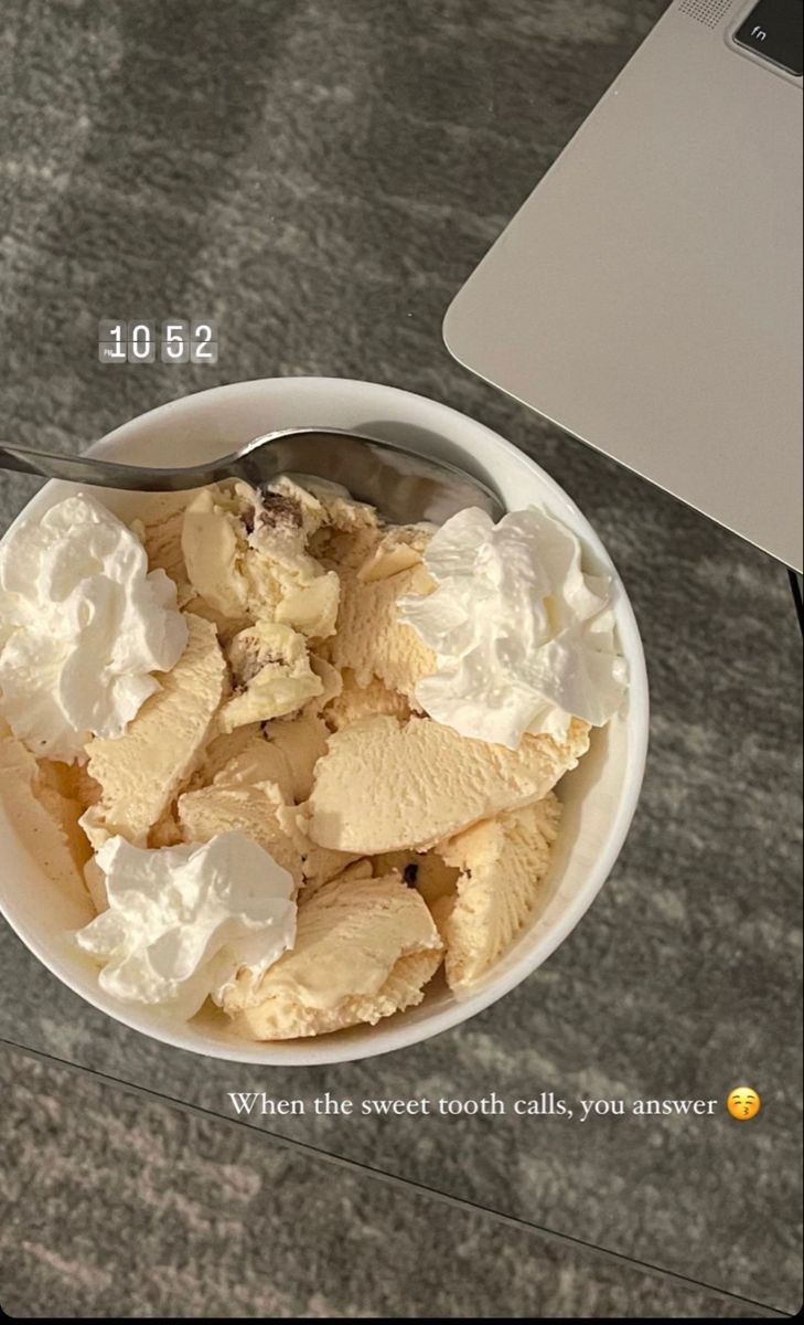 a white bowl filled with ice cream next to a laptop