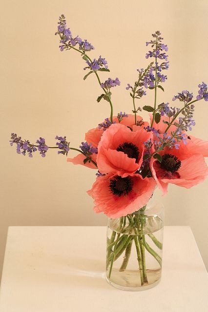 a vase filled with pink and purple flowers on top of a white tableclothed surface