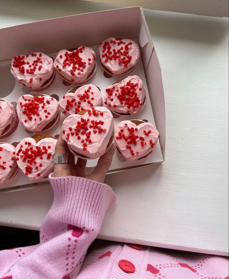 a box filled with heart shaped cupcakes on top of a table