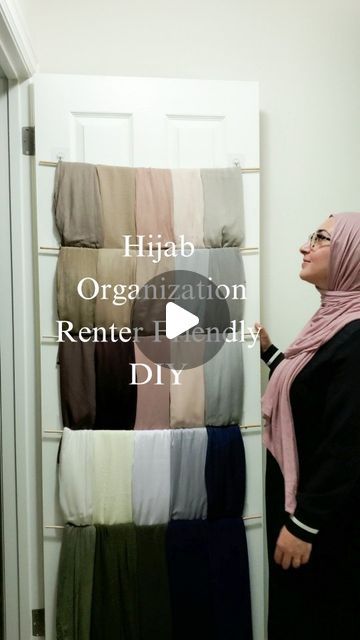 a woman standing in front of a door with her head covered by a pink hijab