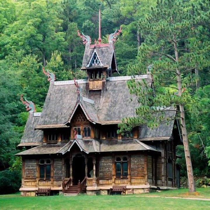 an old wooden house in the middle of a forest with trees and grass around it