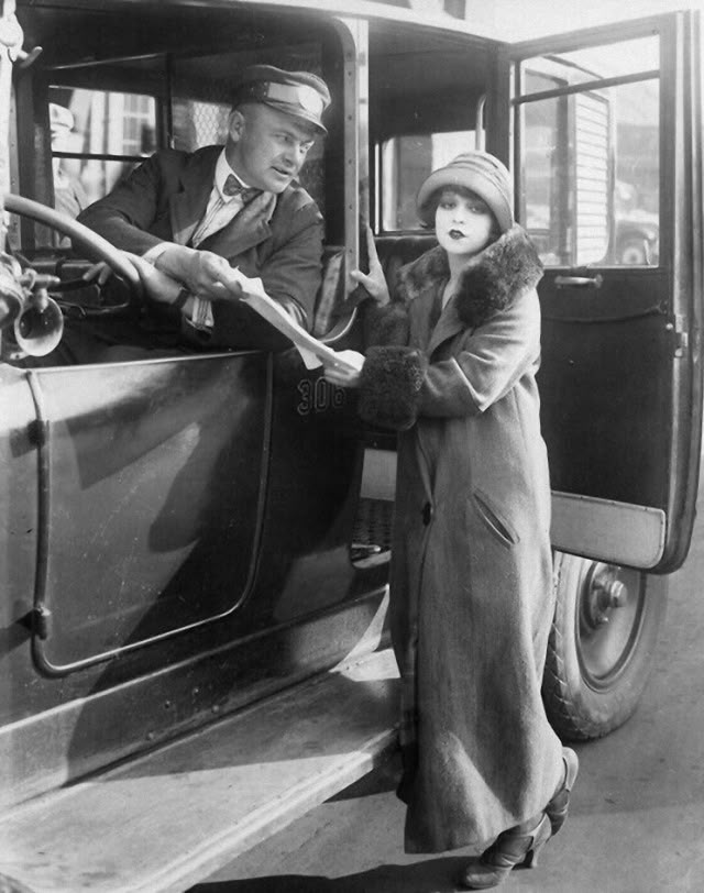 an old black and white photo of two people standing in the door of a bus