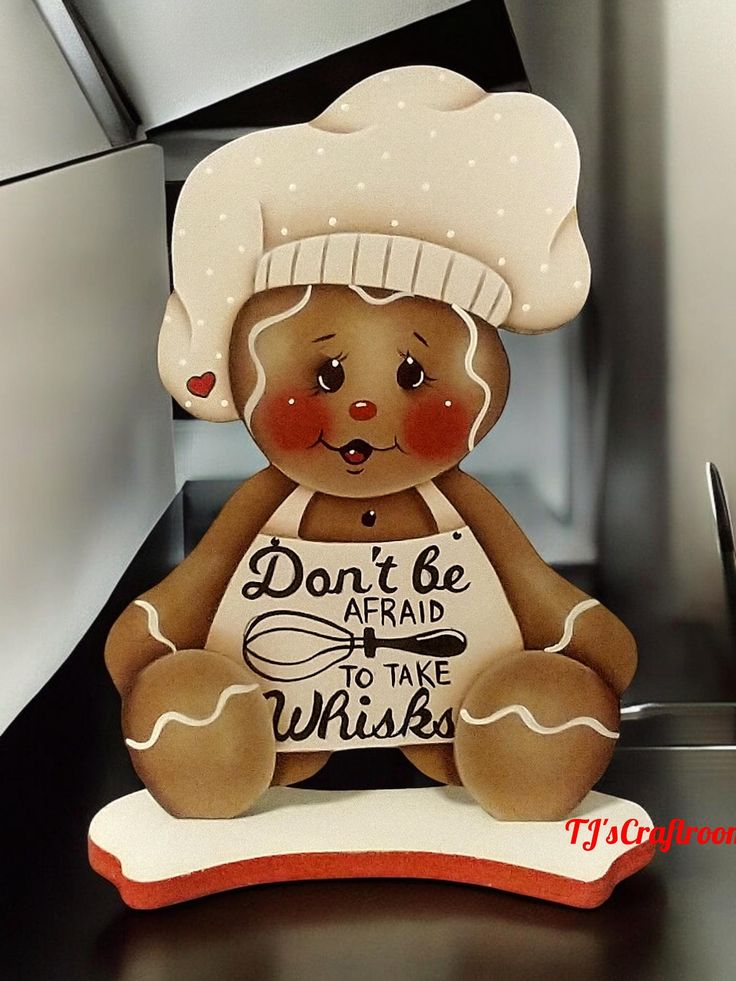 a brown teddy bear wearing a chef's hat and holding a sign that says don't be afraid to take whisks