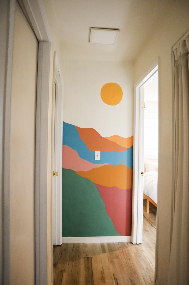 an empty hallway leading to a bedroom with a painting on the wall and wooden floors