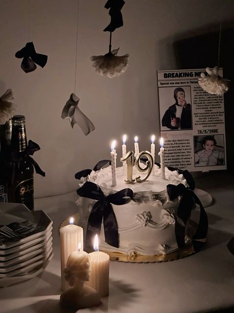 a birthday cake with candles and decorations on the table in front of plates, wine bottles and pictures