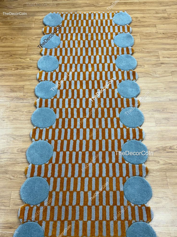 an orange and blue rug with circles on the floor in front of a wooden floor