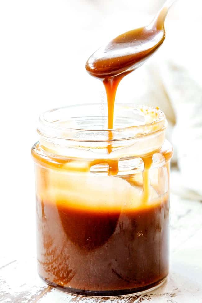 caramel sauce being drizzled on top of an open jar with a spoon