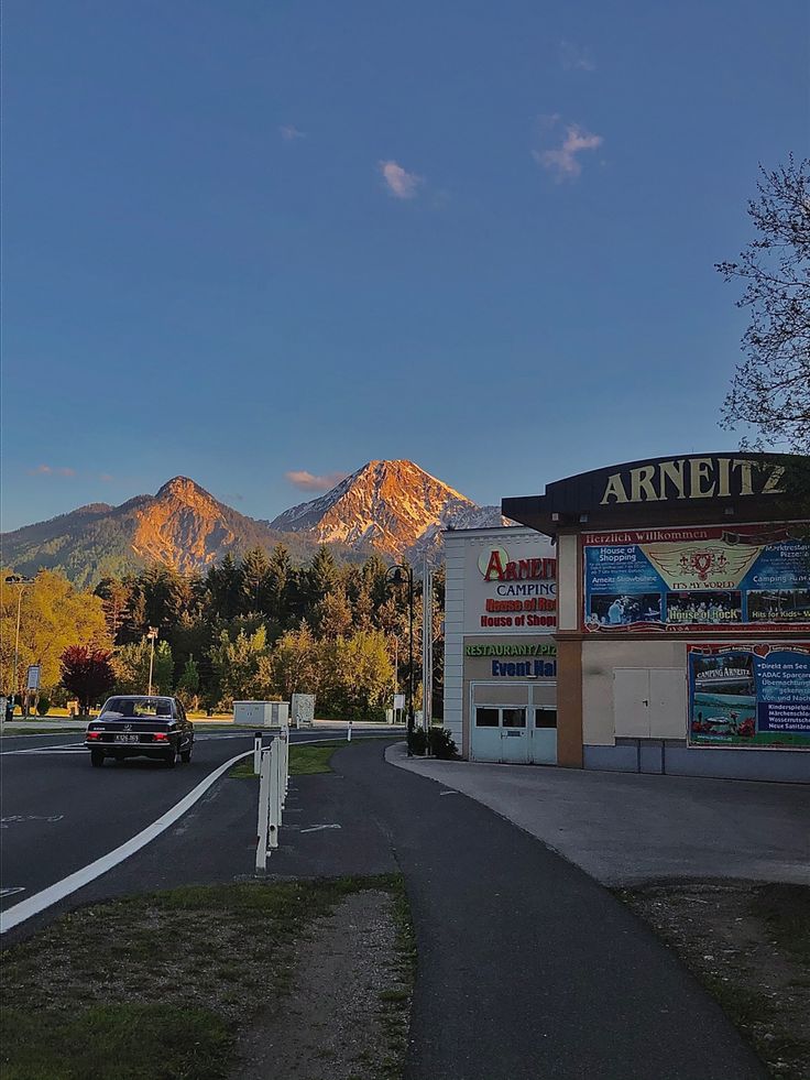 an empty street in front of a store with mountains in the background