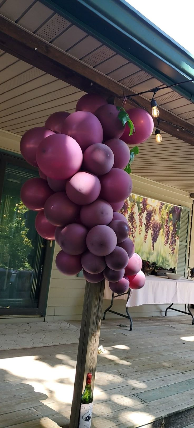 a bunch of balloons are hanging from a pole on the porch with chairs and tables in the background