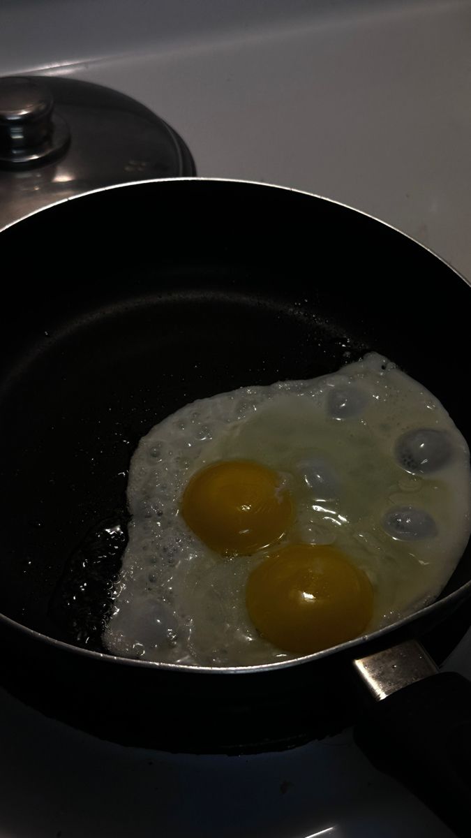 two eggs frying in a pan on the stove