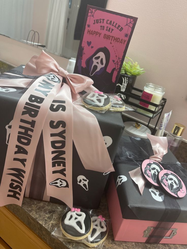 two presents wrapped in pink and black ribbon on top of a counter next to a mirror