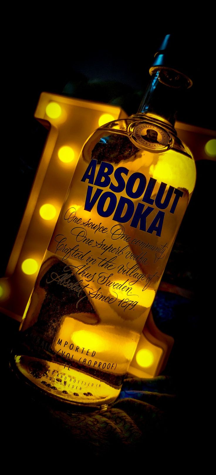 a bottle of absolut vodka sitting on top of a table next to some lights