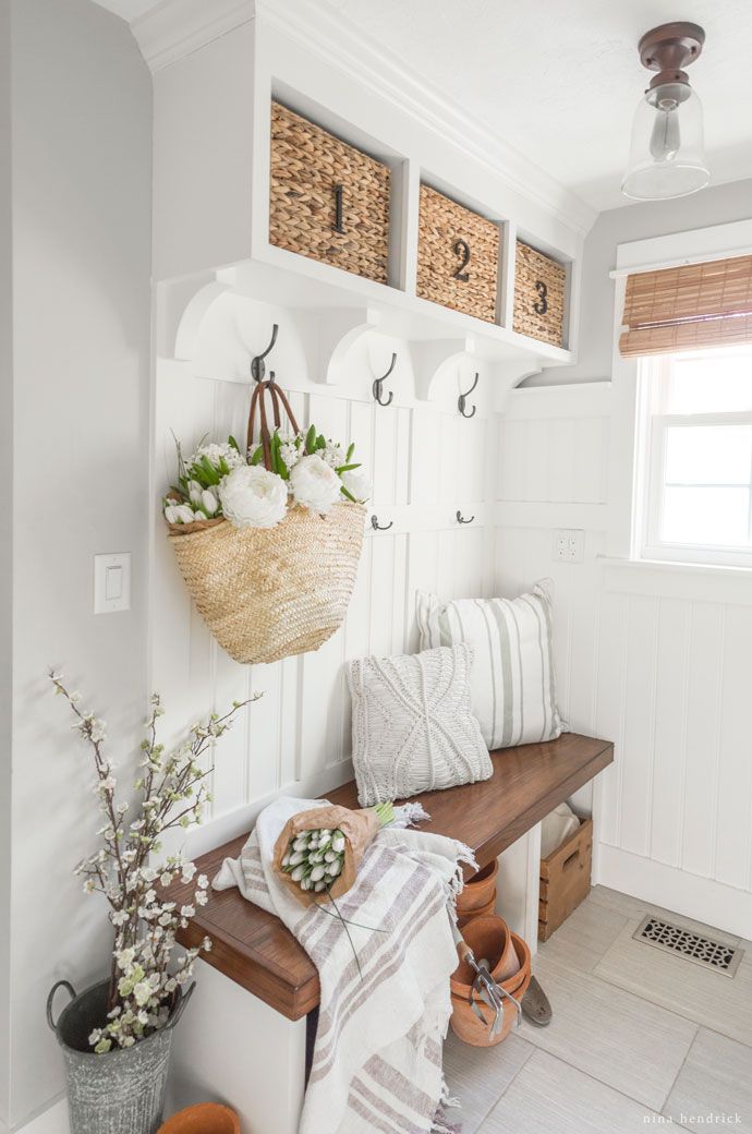 a wooden bench sitting under a window next to a basket filled with flowers and plants