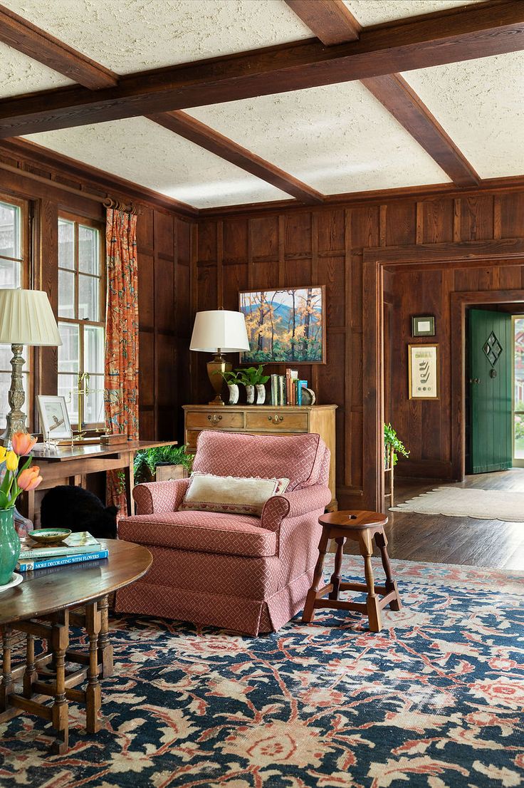 a living room with wood paneling and pink chair in the middle of the room