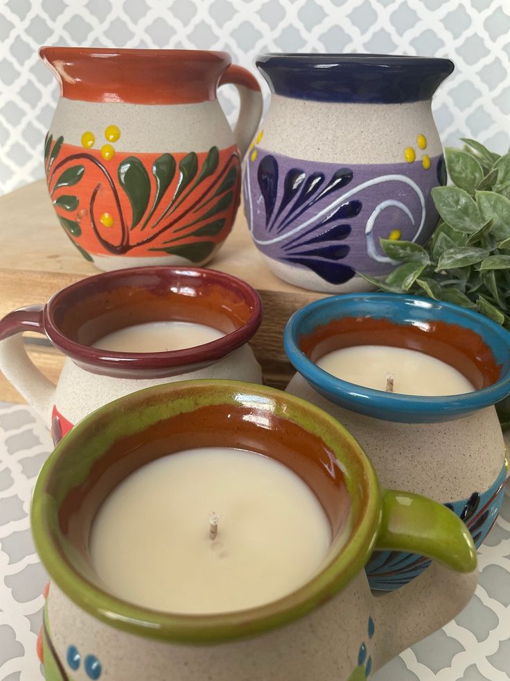 three mugs filled with liquid sitting next to each other on a tablecloth covered surface