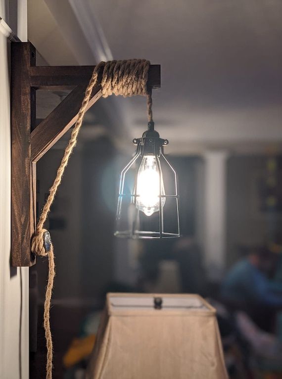 a light hanging from the side of a wall next to a lamp on a rope