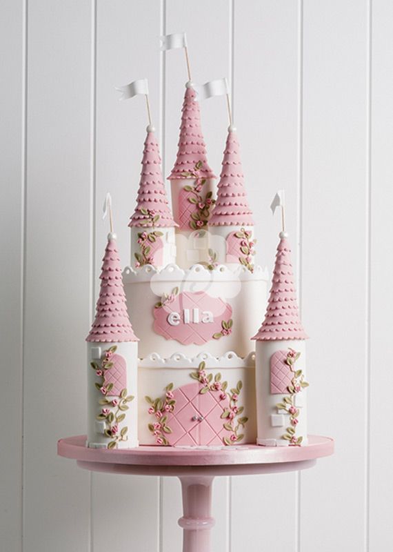 a pink and white castle cake on top of a table