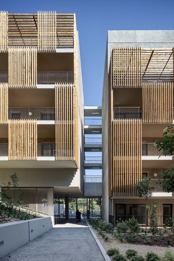 two tall buildings with wooden balconies on the sides and plants growing in front