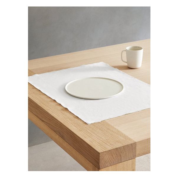 a white plate sitting on top of a wooden table next to a cup and saucer