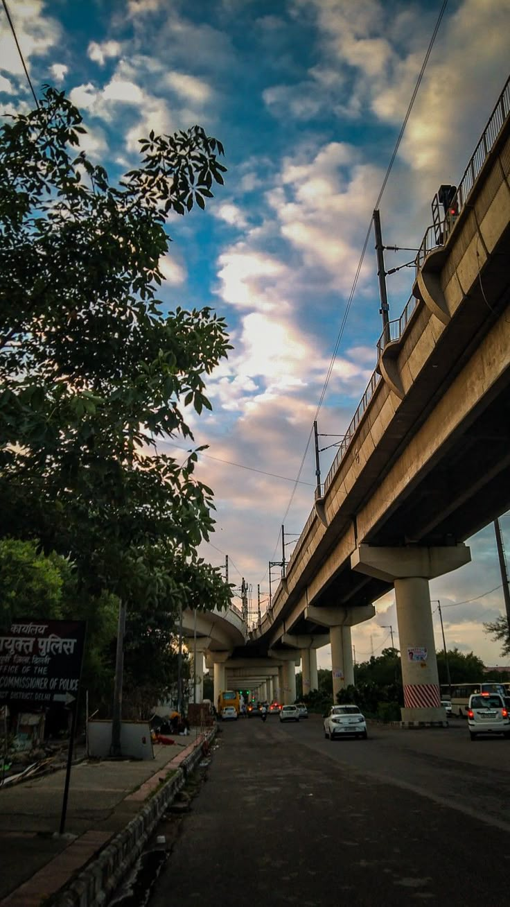 cars are parked on the side of an empty street under a bridge with power lines above it