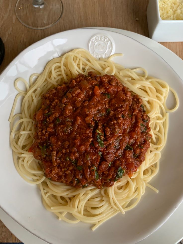 spaghetti with sauce and parmesan cheese on a white plate