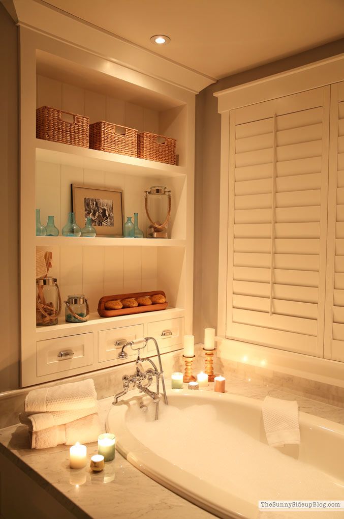 a bath tub sitting next to a shelf filled with candles