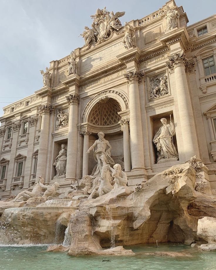 an ornate building with statues and fountains in front