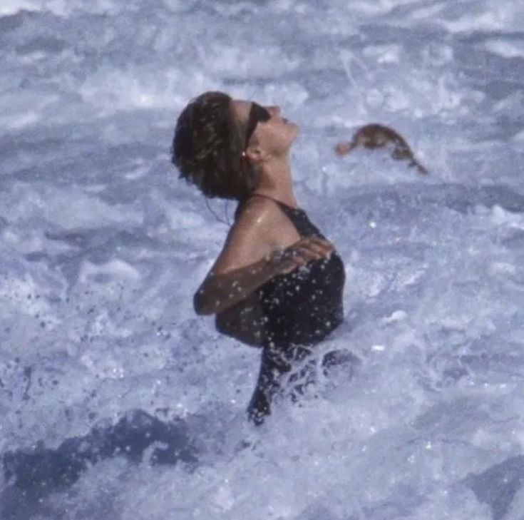 a woman standing in the ocean with her eyes closed