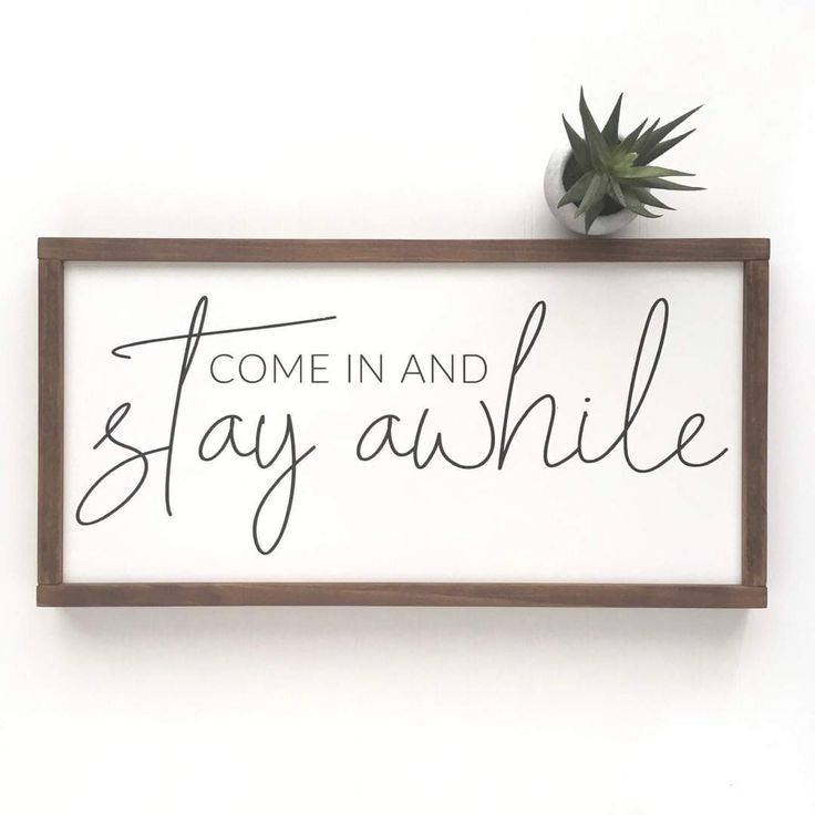 a wooden sign that says, come in and stay awhile on the wall next to a potted plant