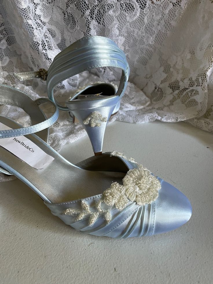 a pair of white shoes sitting on top of a table next to a lace covered curtain