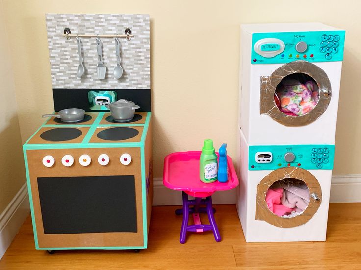 two play kitchen sets sitting next to each other on the floor in front of a wall