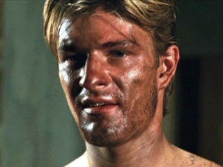 a close up of a man with mud on his face and chest, looking at the camera