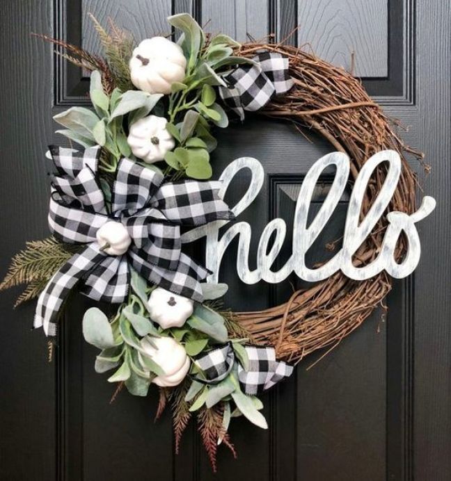 a black and white wreath with the word hello painted on it is hanging on a door