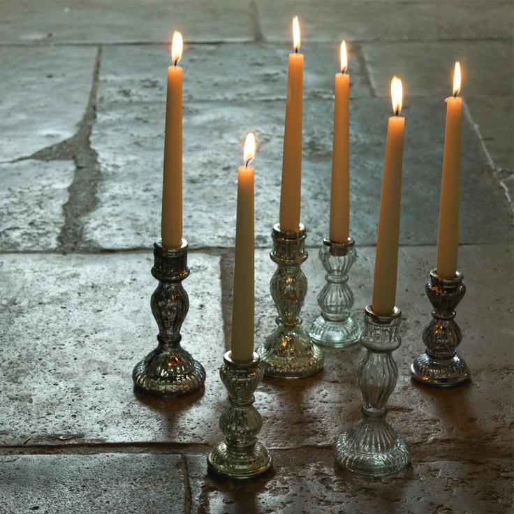 a group of candles sitting next to each other on top of a stone floor in front of a building